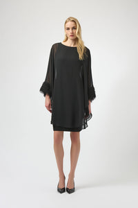 Joseph Ribkoff black silky knit and chiffon layered dress with fringe cuff detail, boat neckline and dolman sleeves, elegant women’s occasion dress at Hollie Rose.
