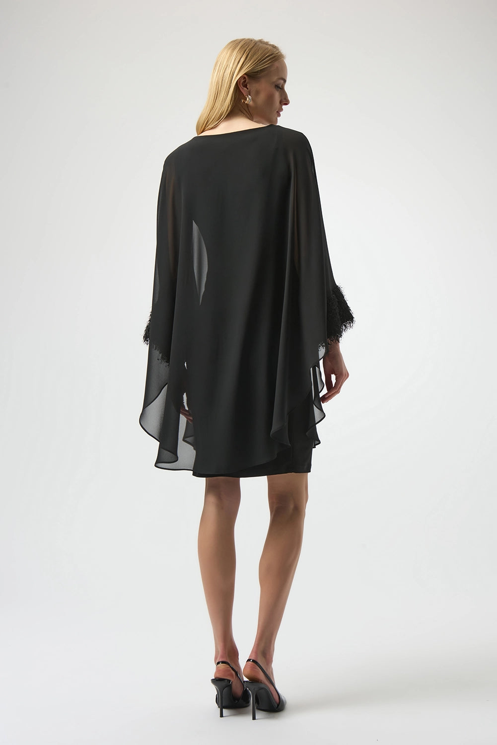 Joseph Ribkoff black silky knit and chiffon layered dress with fringe cuff detail, boat neckline and dolman sleeves, elegant women’s occasion dress at Hollie Rose.
