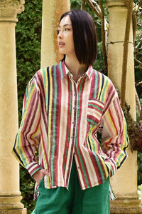Person wearing a colorful striped shirt and green pants standing outdoors.