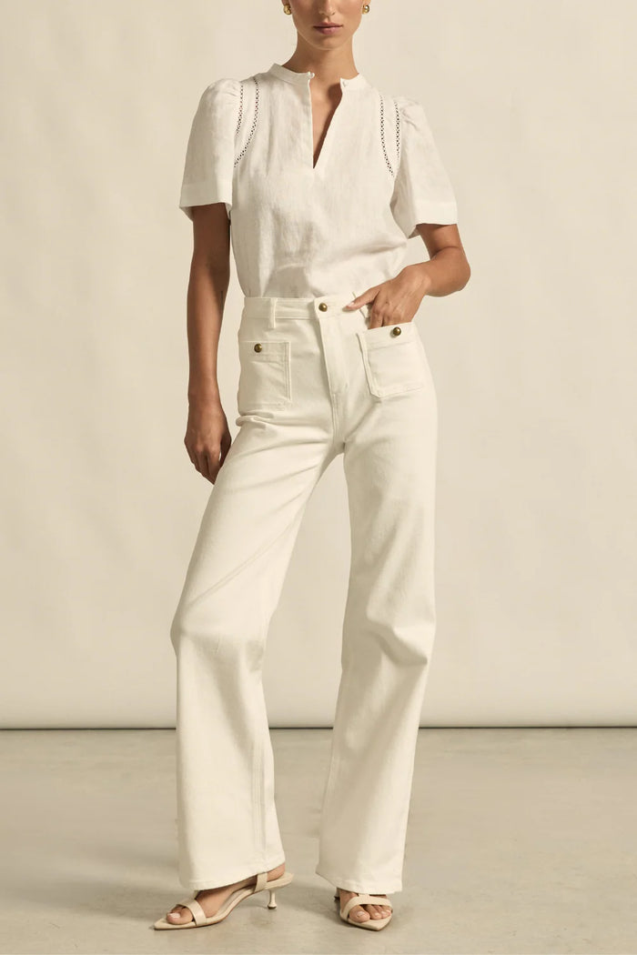 Person wearing a white outfit with wide-leg pants against a neutral background